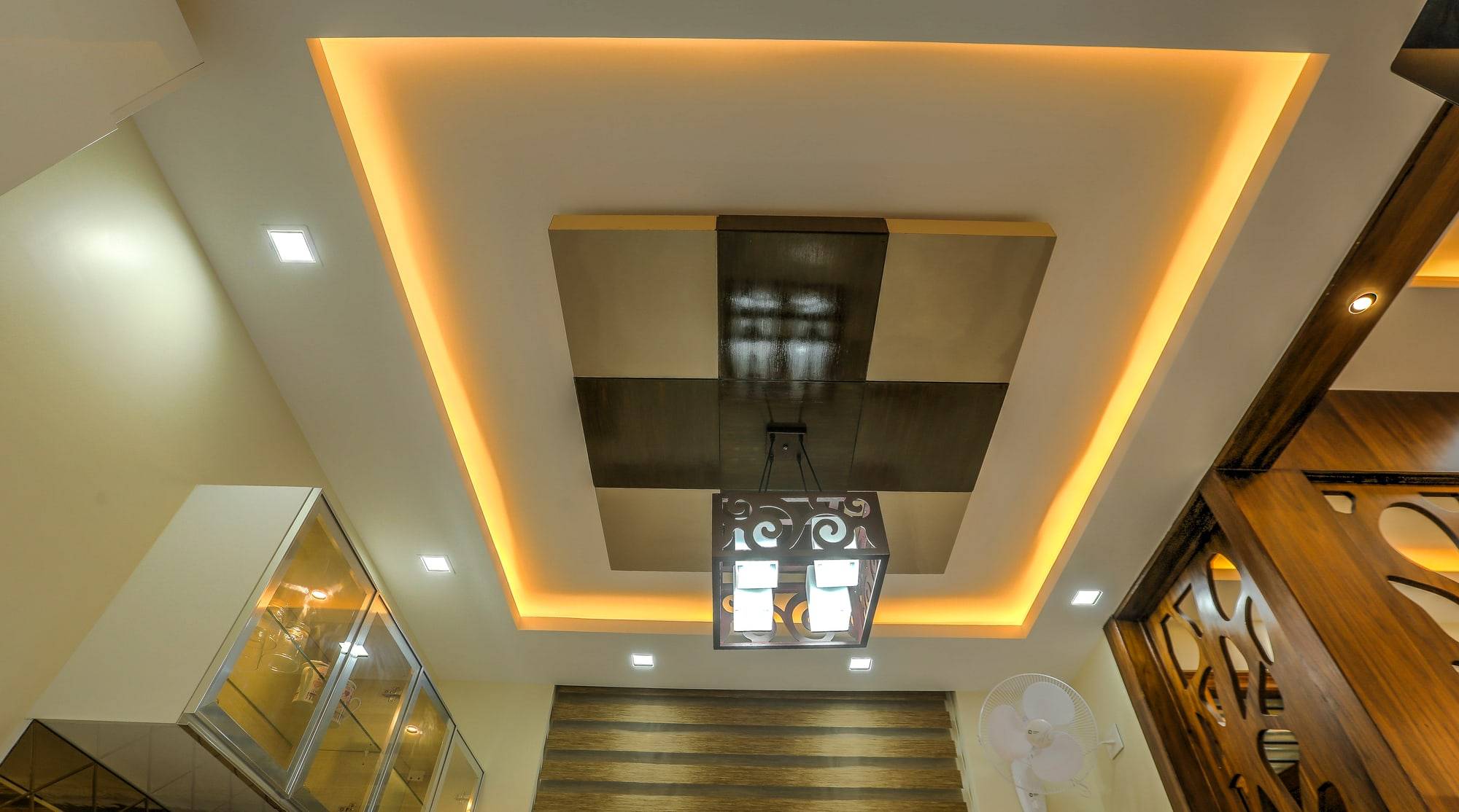 Dining false ceiling with perimeter amber cove lighting and metal pendant