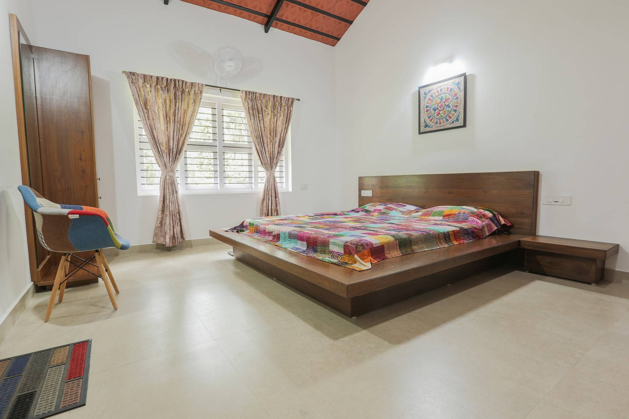 Master bedroom with low solid wood platform bed and pitched ceiling